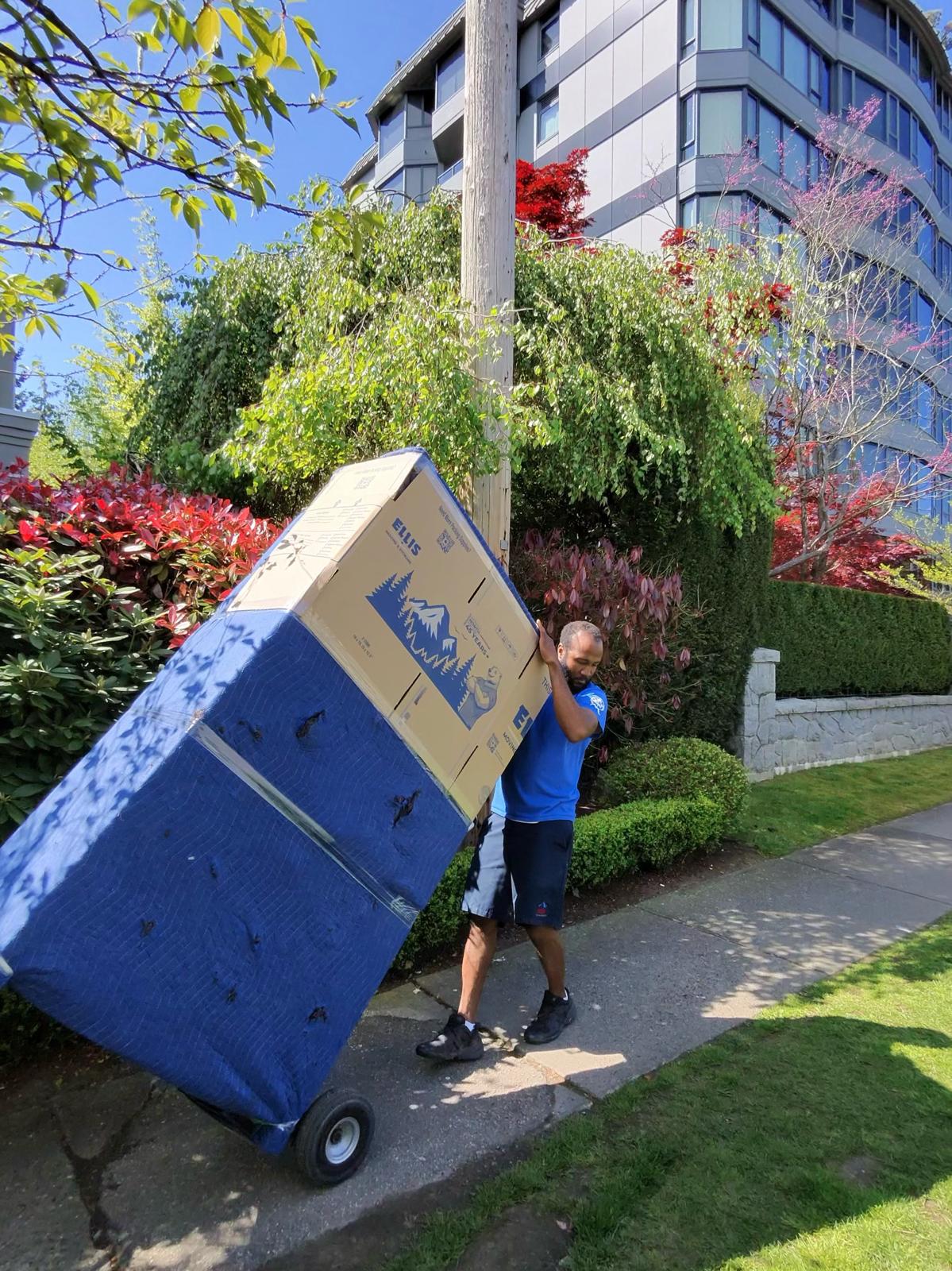 Ellis mover wheeling a blanket-wrapped load past a North Vancouver condo tower
