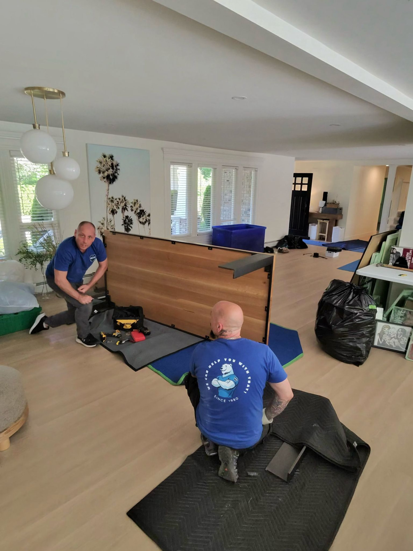 Ellis movers protecting floors and disassembling furniture inside a North Vancouver home
